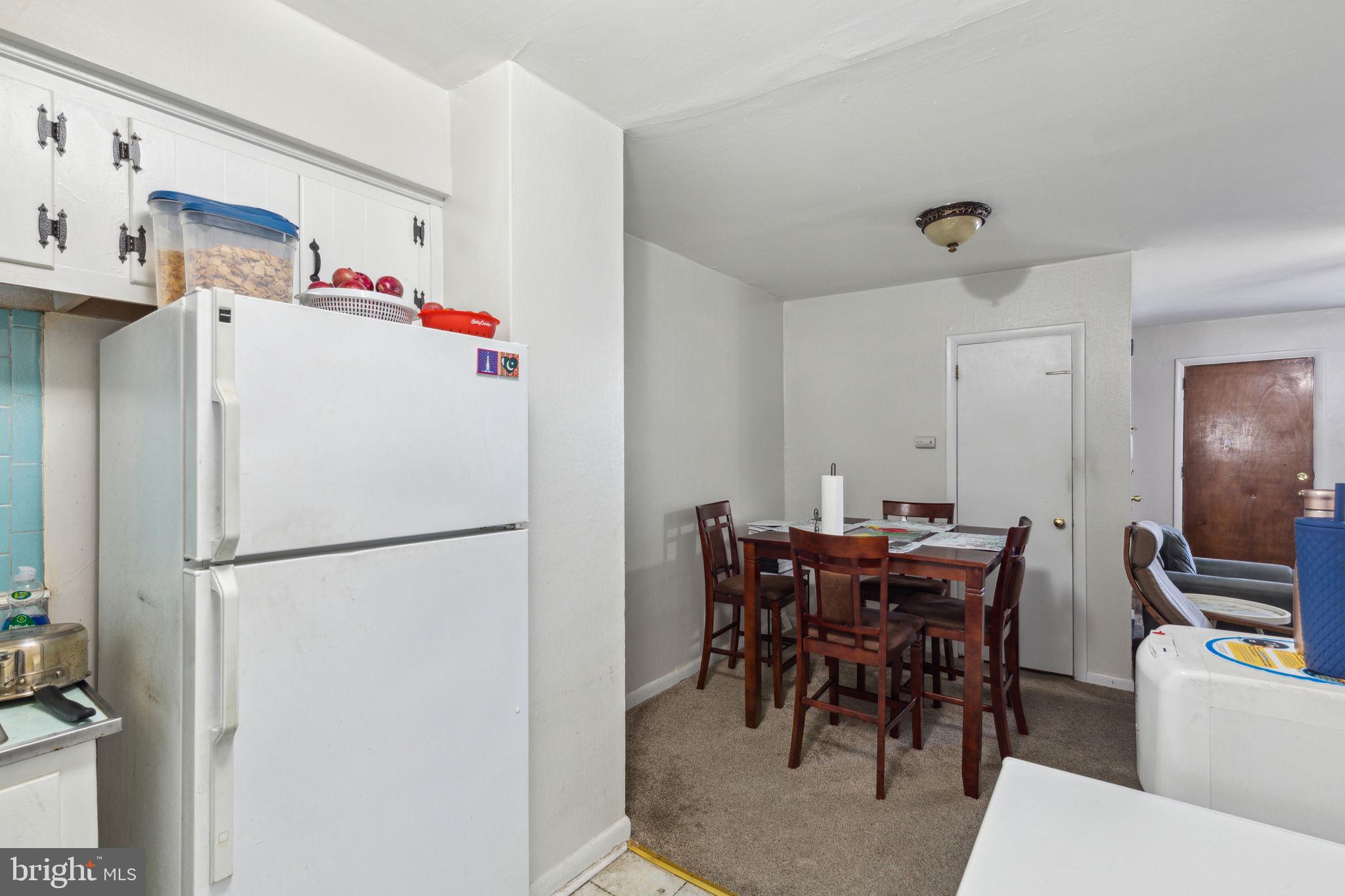 392 Beverly Boulevard Upper Darby, PA 19082 - Photo 9 of 26 a white kitchen with a refrigerator a dining table and chairs