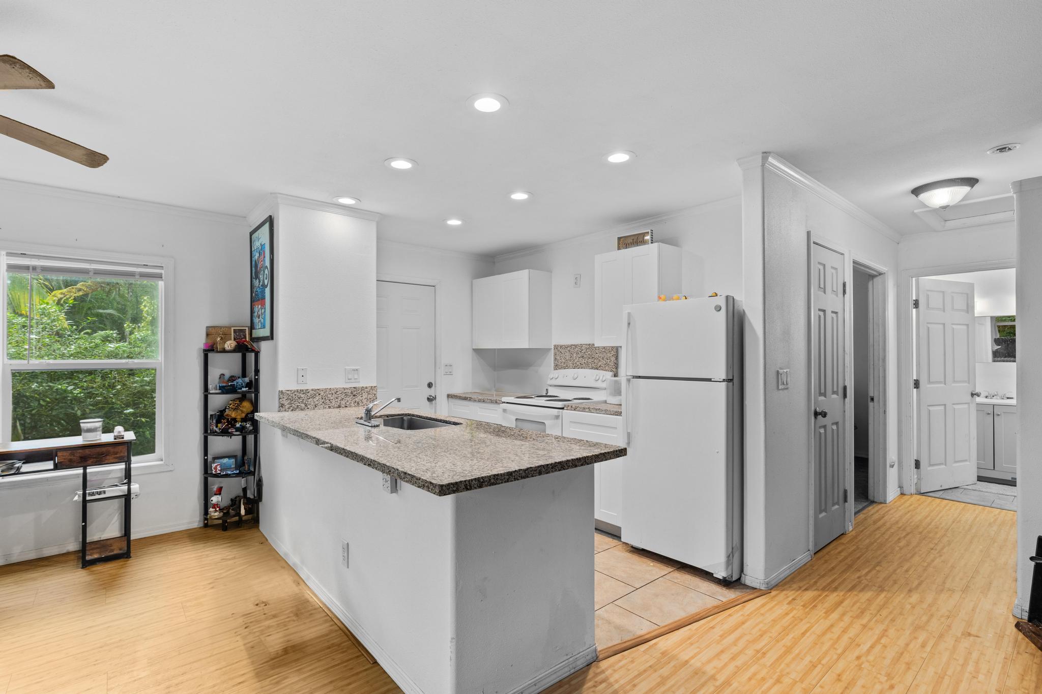 14-823 Seaview Road Pahoa, HI 96778 - Photo 7 of 23 a kitchen with stainless steel appliances granite countertop a refrigerator a sink dishwasher and a stove with wooden floor