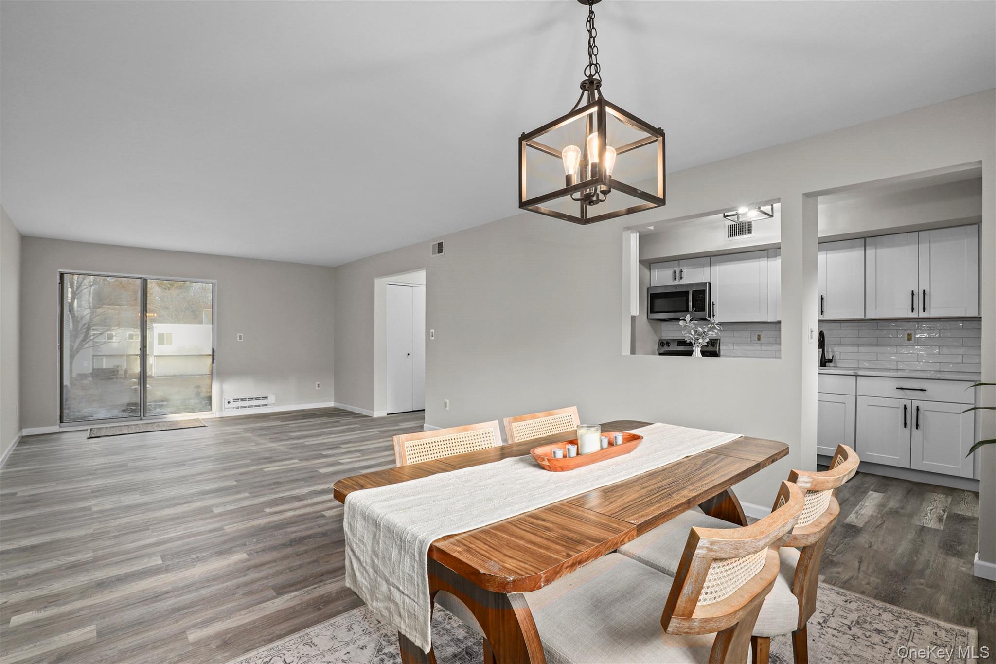 208 Harris Road, Unit D4A Bedford Hills, NY 10507 - Photo 4 of 13 a dining room with wooden floor a chandelier a wooden table and chairs