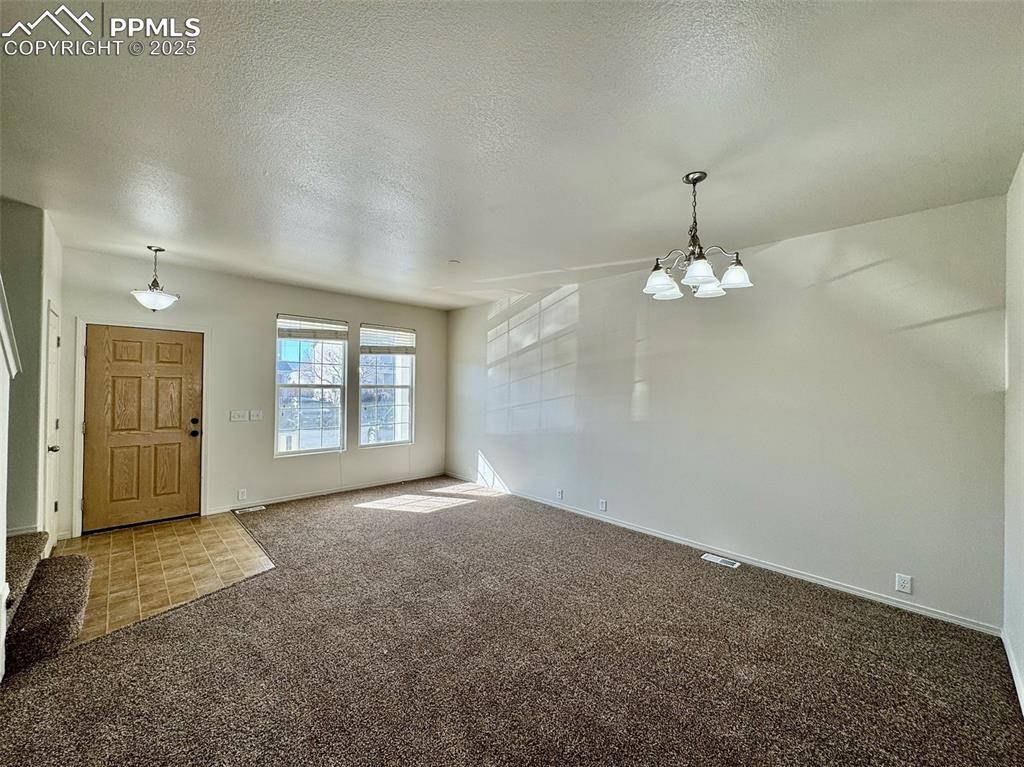 7354 Countryside Grove Fountain, CO 80817 - Photo 4 of 28 en empty room with windows and chandelier fan