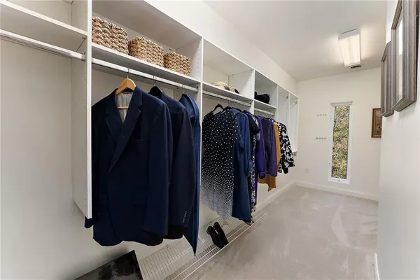 a view of walk in closet with clothes and shoes