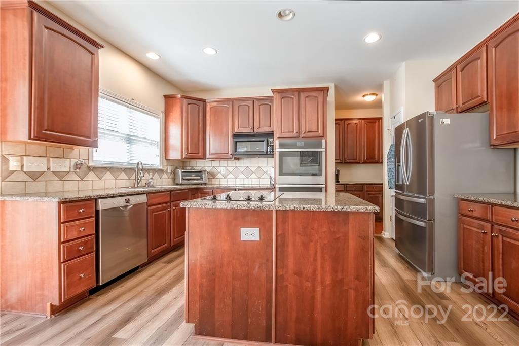 5511 Alexandrite Way Fort Mill, SC 29708 - Photo 8 of 32 a kitchen with stainless steel appliances granite countertop a refrigerator a sink dishwasher a stove with wooden cabinets and floor