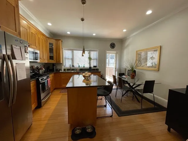 a kitchen with stainless steel appliances granite countertop a sink a stove a refrigerator cabinets and chairs