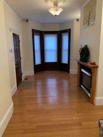 a view of an empty room with wooden floor and a fireplace