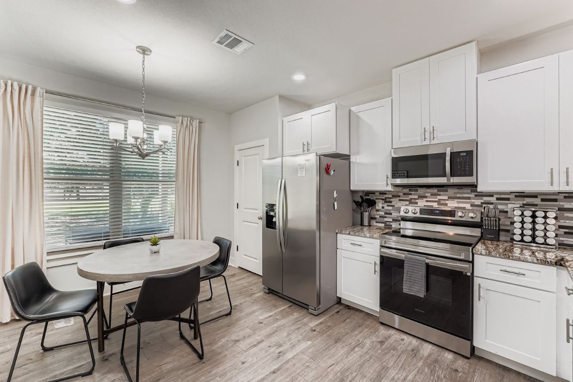 18803 Hogan Circle, Unit 14 Point Venture, TX 78645 - Photo 12 of 40 a kitchen with stainless steel appliances wooden floor dining table and chairs