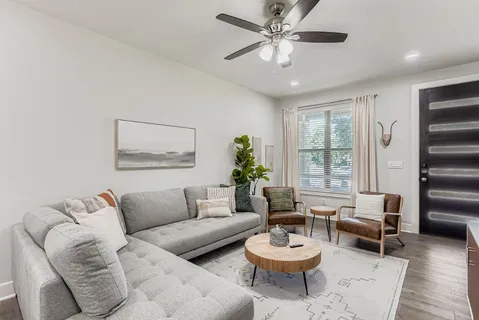 a living room with furniture a ceiling fan and a flat screen tv
