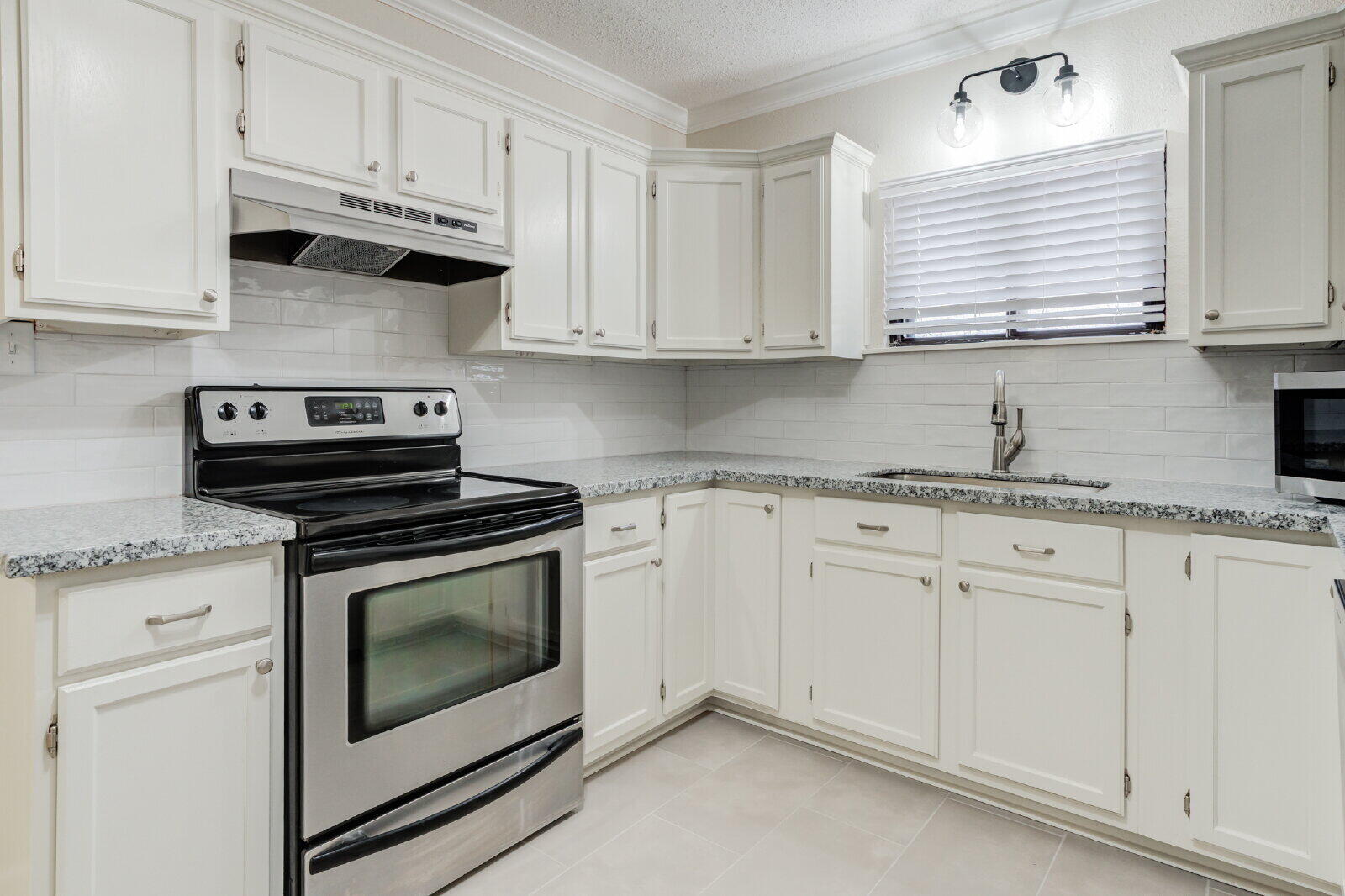 2602 24th Street Lubbock, TX 79410 - Photo 17 of 37 a kitchen with granite countertop white cabinets and white stainless steel appliances