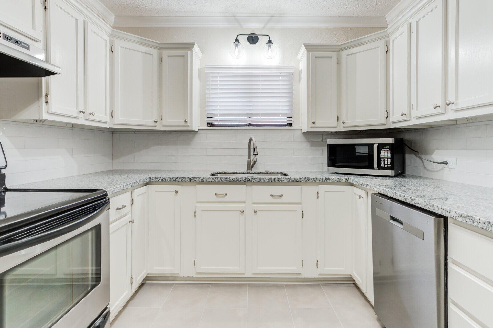 2602 24th Street Lubbock, TX 79410 - Photo 18 of 37 a kitchen with granite countertop white cabinets stainless steel appliances and sink