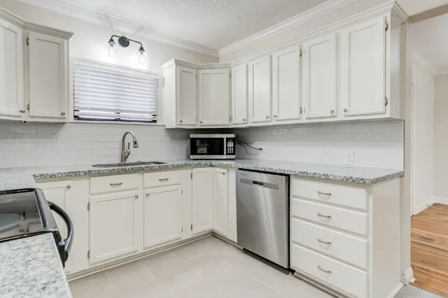 a kitchen with granite countertop white cabinets and sink