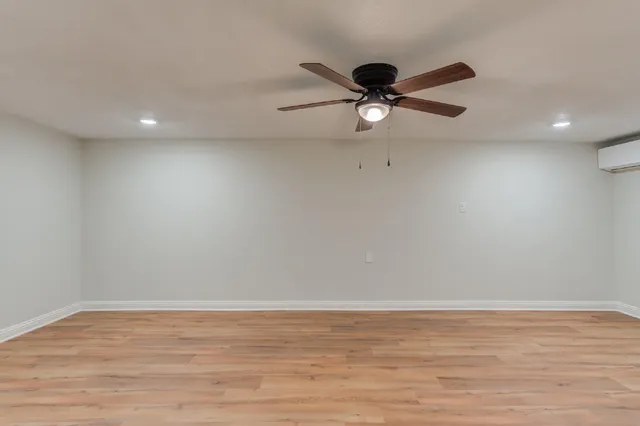 a view of a big room with wooden floor and a ceiling fan