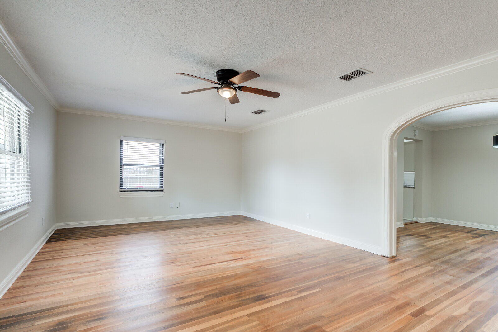 2602 24th Street Lubbock, TX 79410 - Photo 6 of 37 an empty room with wooden floor chandelier fan and windows