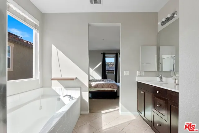 a en suite bathroom with a tub double vanity sink and a mirror