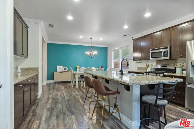 a kitchen with cabinets a sink dishwasher a dining table and chairs with wooden floor