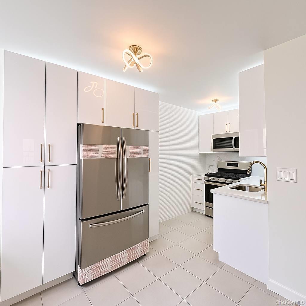 65-70 Booth Street, Unit 5E Queens, NY 11374 - Photo 2 of 5 a kitchen with stainless steel appliances granite countertop a refrigerator a stove a sink and a refrigerator
