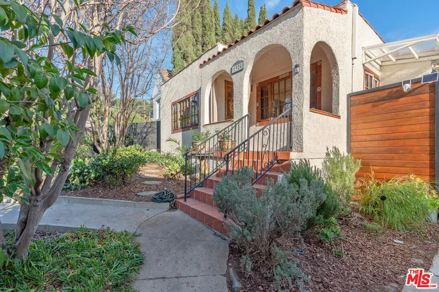 a front view of a house with plants and trees