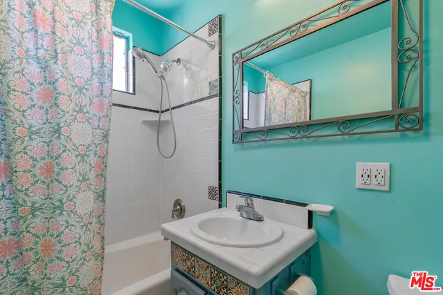 a bathroom with a sink and mirror with bathtub