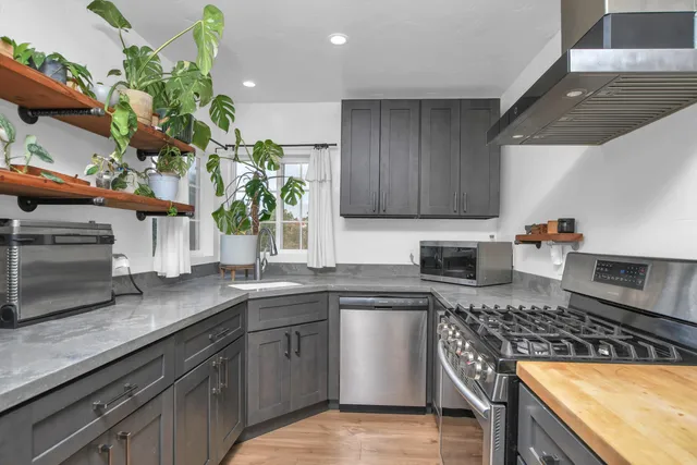 a kitchen with stainless steel appliances granite countertop a sink a stove top oven a counter space and cabinets