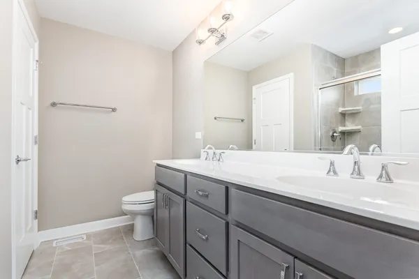 a spacious bathroom with a double vanity sink toilet and a mirror