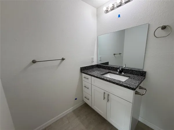 a bathroom with a granite countertop sink and white cabinets