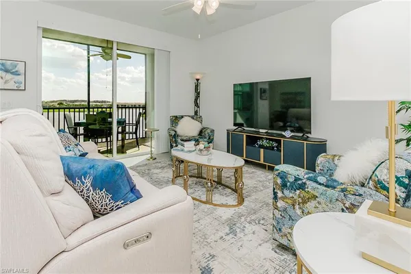 a living room with furniture a flat screen tv and a large window