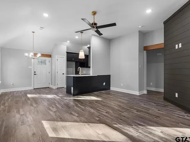 a view of kitchen and empty room with wooden floor