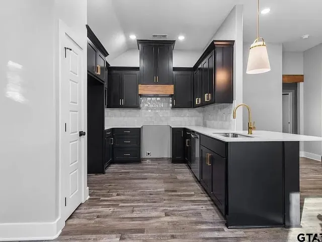 a large kitchen with stainless steel appliances kitchen island granite countertop a refrigerator and a sink