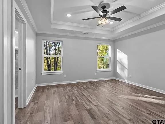a view of an empty room with window and wooden floor