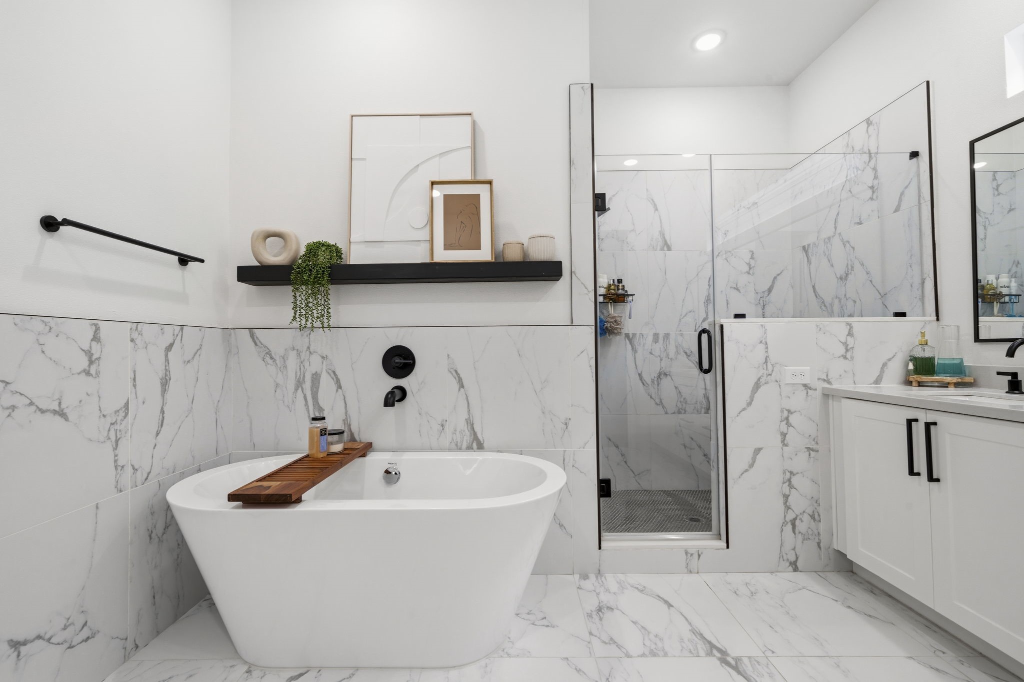 9018 Wellspring Drive Houston, TX 77080 - Photo 13 of 25 Indulge in a true spa experience in the primary bath, featuring a contemporary freestanding soaking tub, a large glass-enclosed walk-in shower with marble-style tile surround, and sleek matte black hardware.