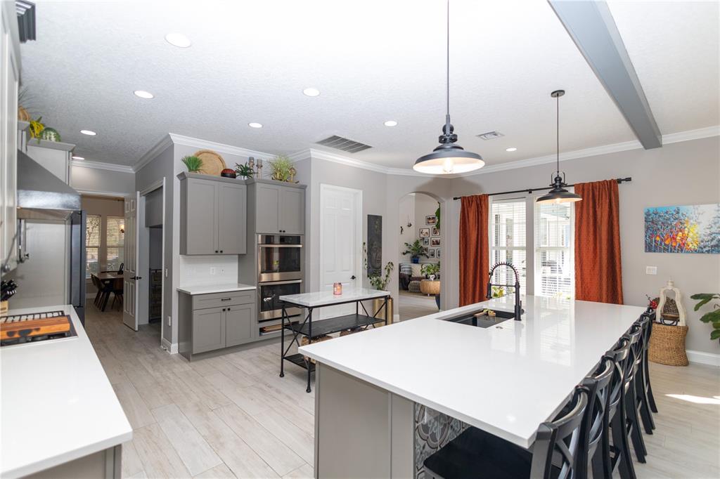 3305 Schoolhouse Road St. Cloud, FL 34773 - Photo 7 of 83 a kitchen with stainless steel appliances kitchen island granite countertop a table chairs refrigerator and sink