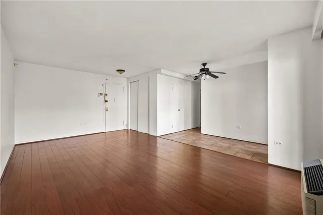 an empty room with wooden floor ceiling fan and windows