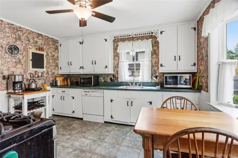 a kitchen with stainless steel appliances granite countertop a stove top oven a sink a dining table and chairs with white cabinets