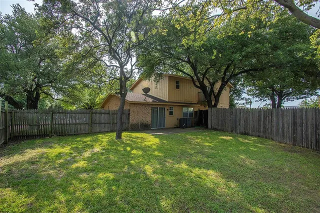 a view of a backyard with large trees and wooden fence