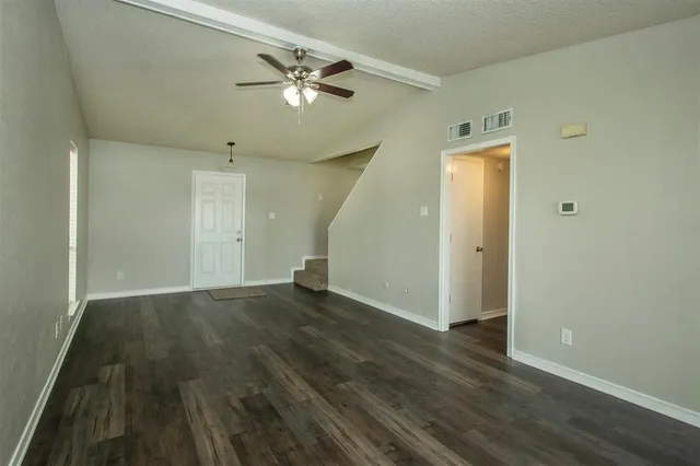 an empty room with wooden floor and chandelier fan