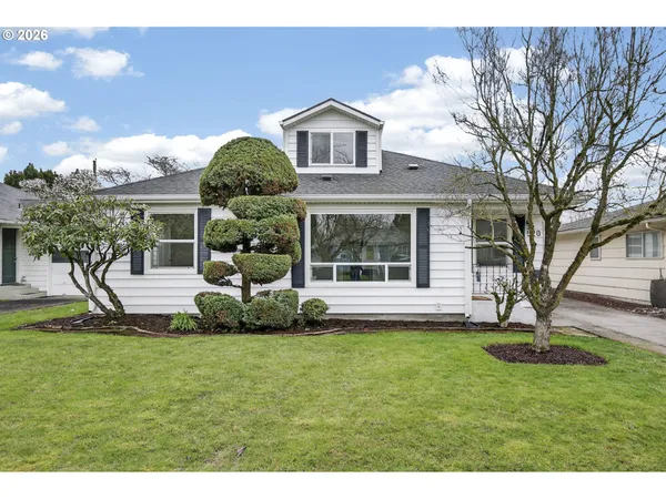a front view of a house with a garden and trees