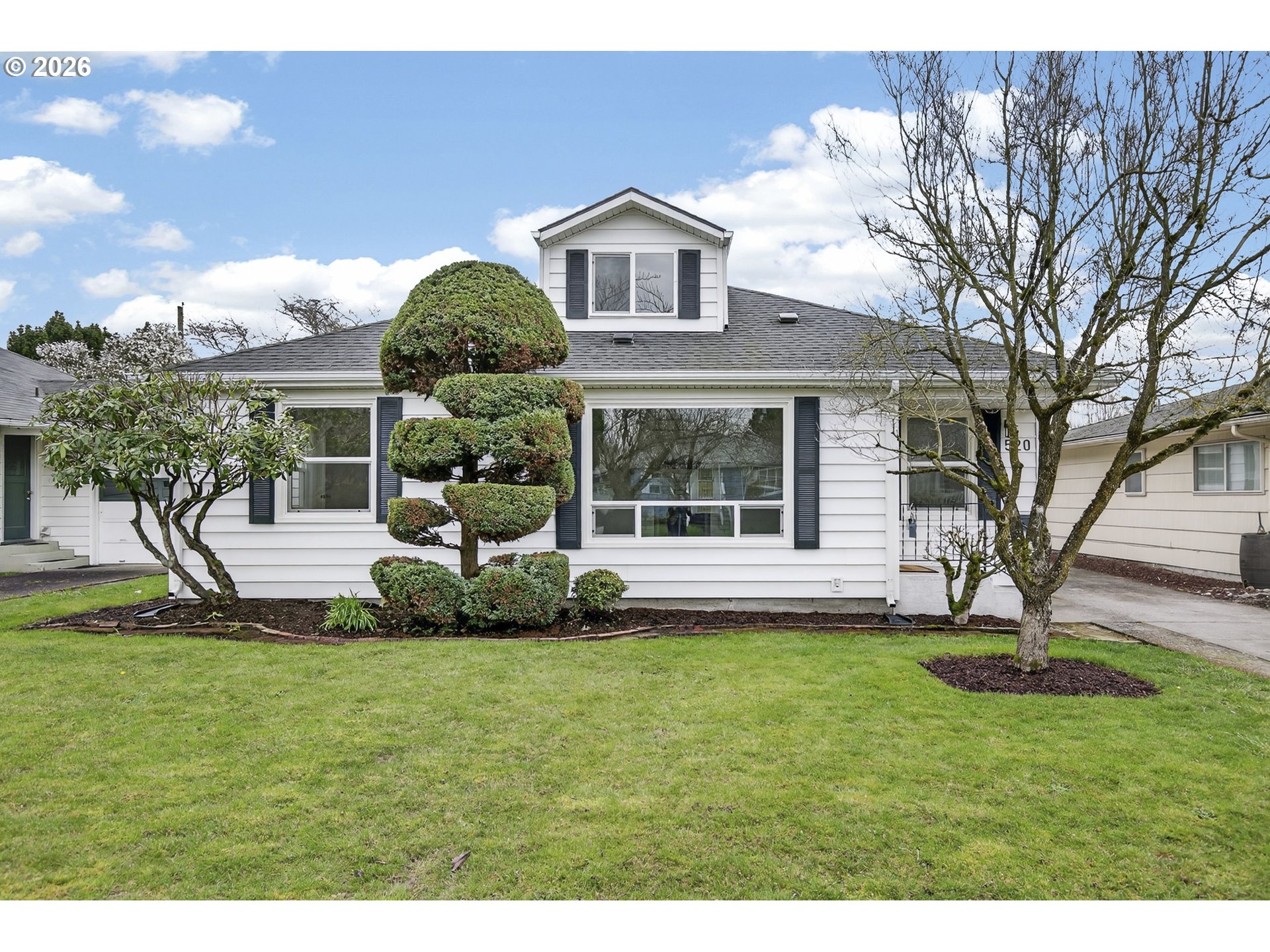 a front view of a house with a garden and trees