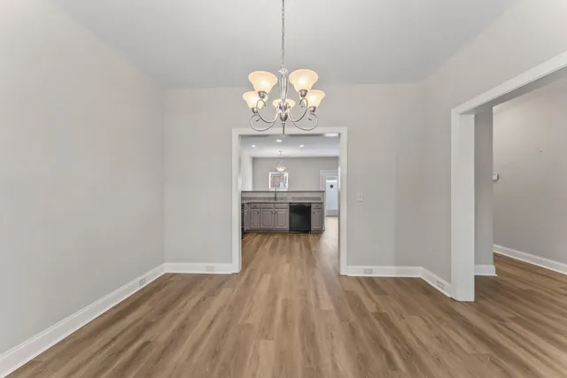 a view of a room with wooden floor chandelier and windows