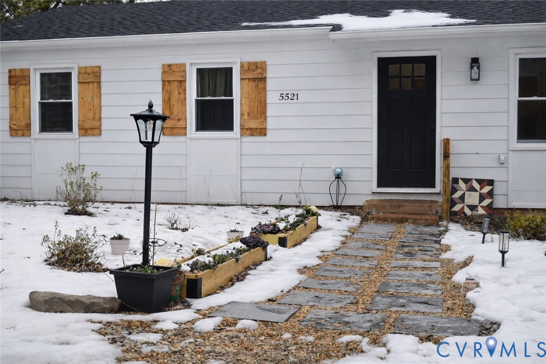 Snow covered property entrance featuring a shingle