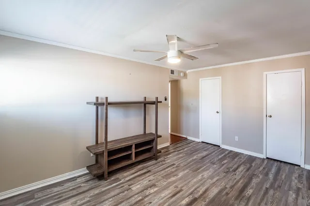 an empty room with wooden floor and a ceiling fan