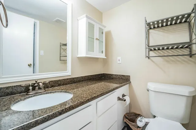 a bathroom with a granite countertop sink a mirror and a toilet