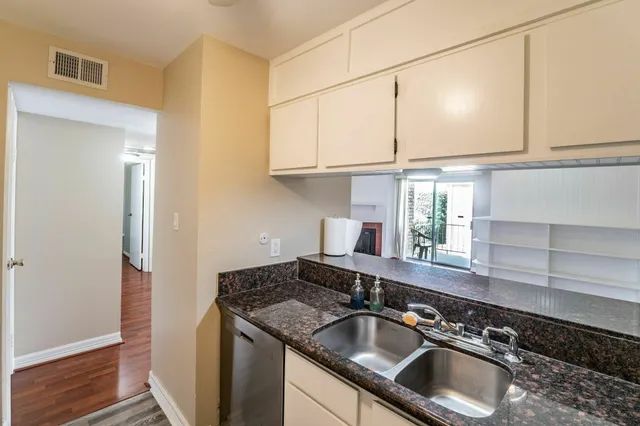 a kitchen with granite countertop a sink and a white cabinets