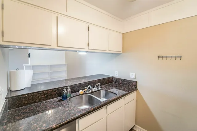 a kitchen with granite countertop a sink a stove and cabinets