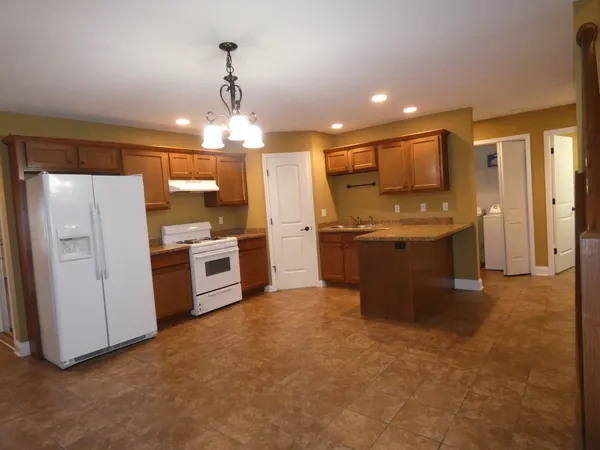 a kitchen with stainless steel appliances kitchen island granite countertop a refrigerator and a stove top oven