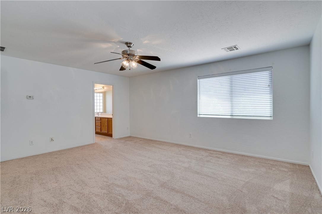 2717 Rimbaud Street Henderson, NV 89044 - Photo 20 of 34 Well-lit and spacious, this room offers plush carpeting and a glimpse into a connected bathroom.