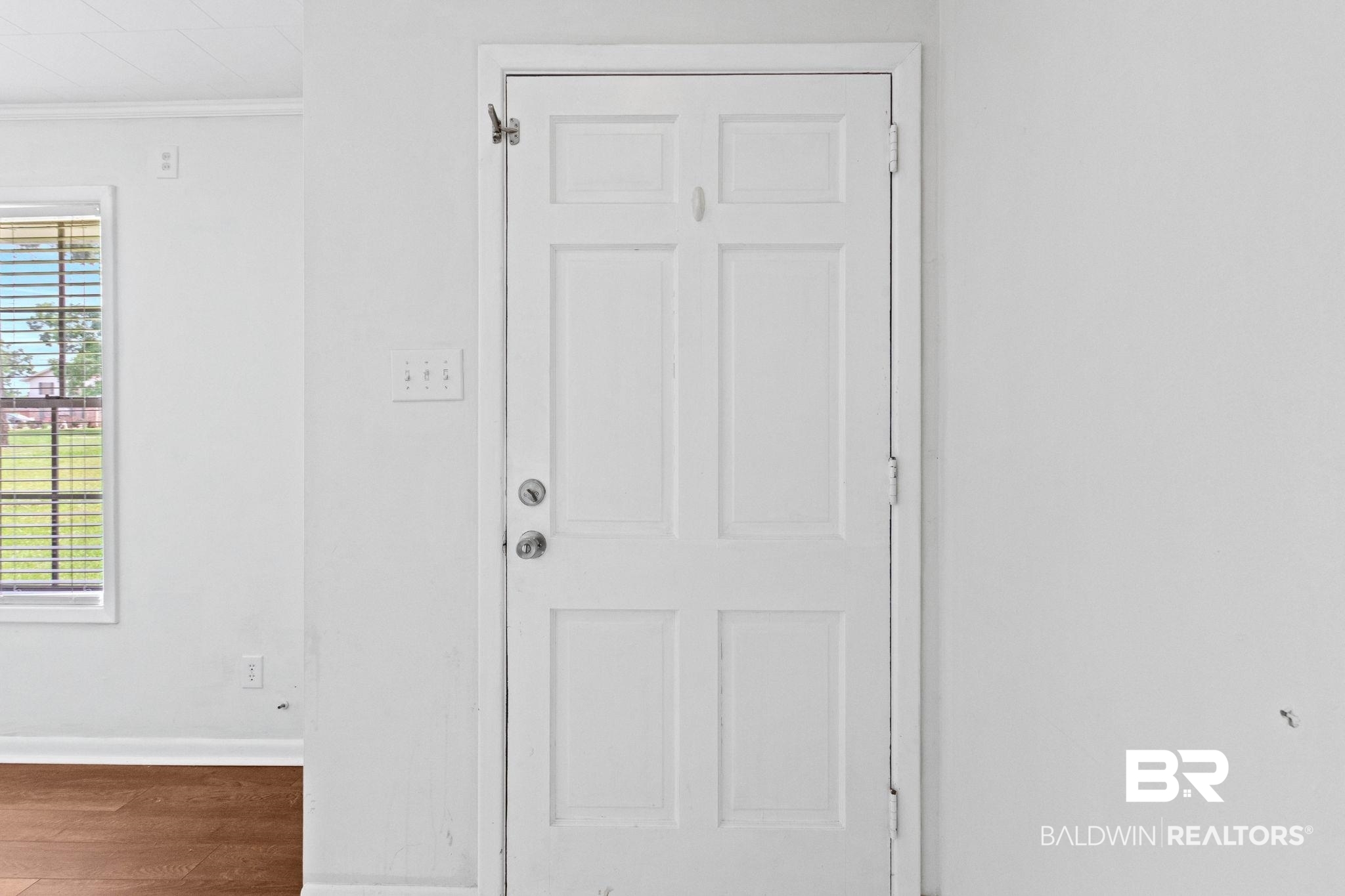 384 Old Bratt Road Atmore, AL 36502 - Photo 7 of 64 White six-panel interior door with chrome hardware, featuring a transom window, baseboard trim, and wood-finish flooring