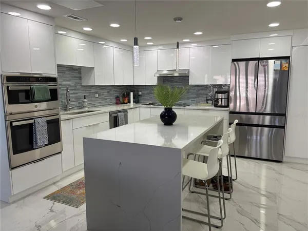 a kitchen with stainless steel appliances granite countertop a refrigerator a stove top oven a sink and a island