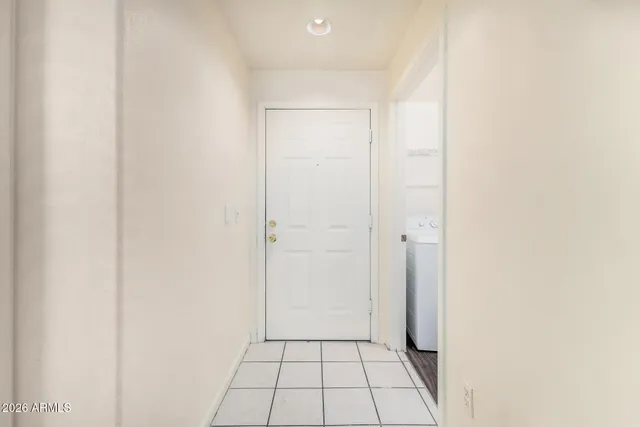 an empty room with wooden floor a ceiling fan and kitchen view