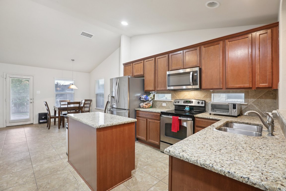1621 Big Thicket Drive Cedar Park, TX 78613 - Photo 11 of 37 a kitchen with granite countertop a sink stove and microwave