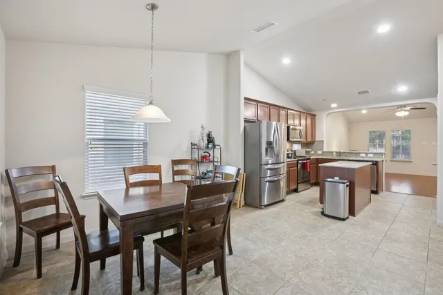 a kitchen with a dining table chairs and refrigerator