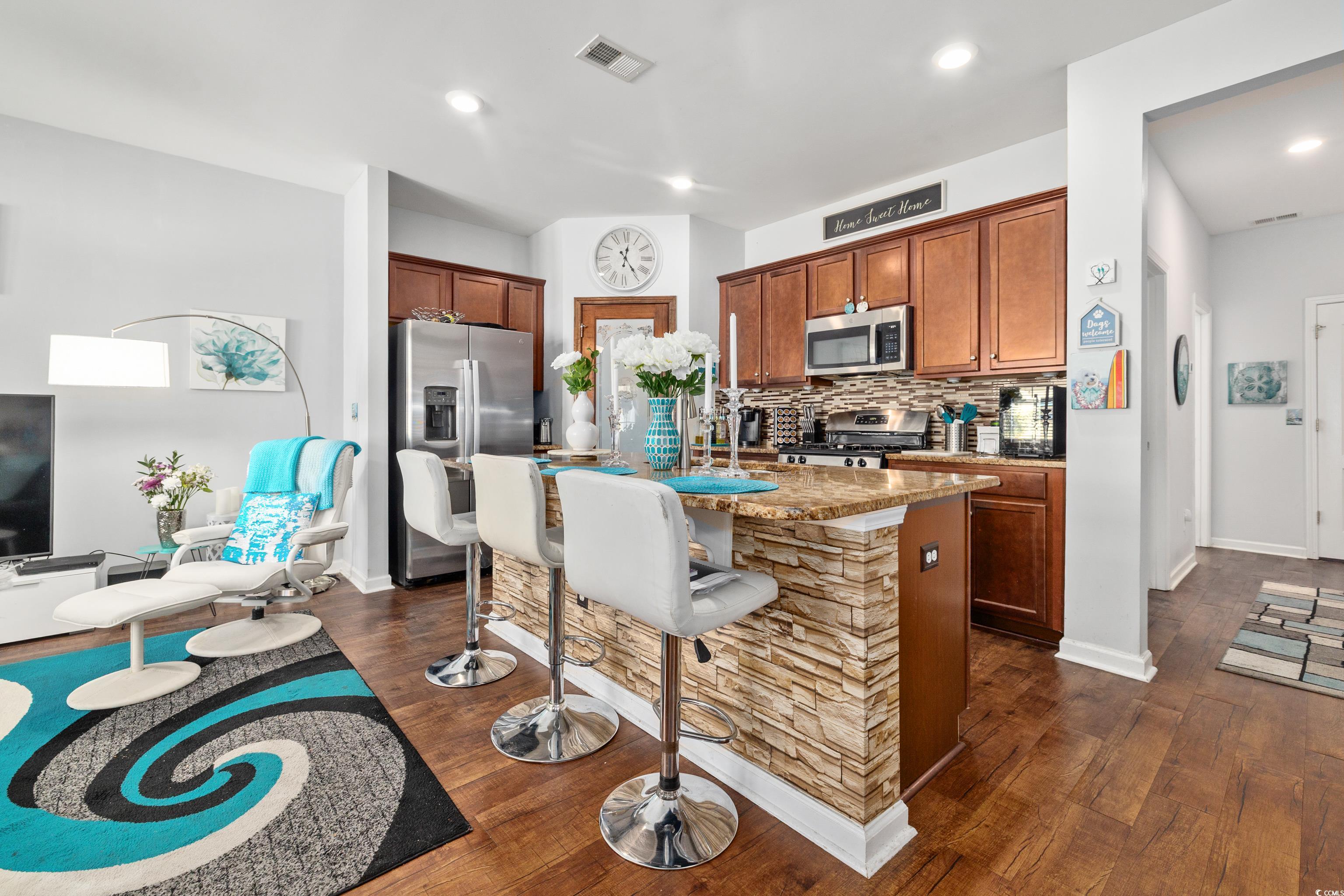 2360 Heritage Loop, Unit 2360 Myrtle Beach, SC 29577 - Photo 18 of 38 Kitchen with stainless steel appliances, a breakfast bar area, backsplash, brown cabinets, and light stone counters