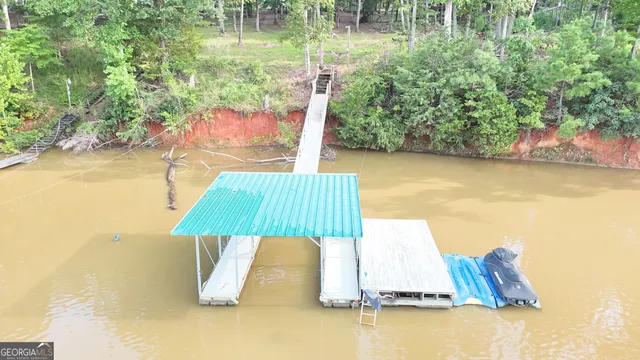 a view of a lake with lawn chairs and large trees